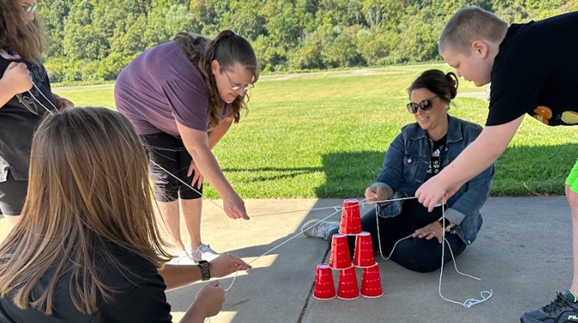 Students participating in a STEM cup stacking activity with staff