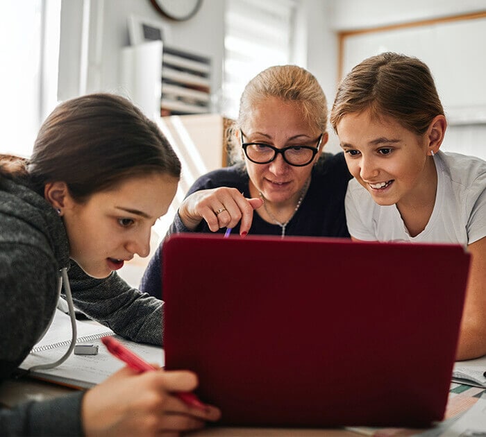 A mother is helping her two daughters with online classwork
