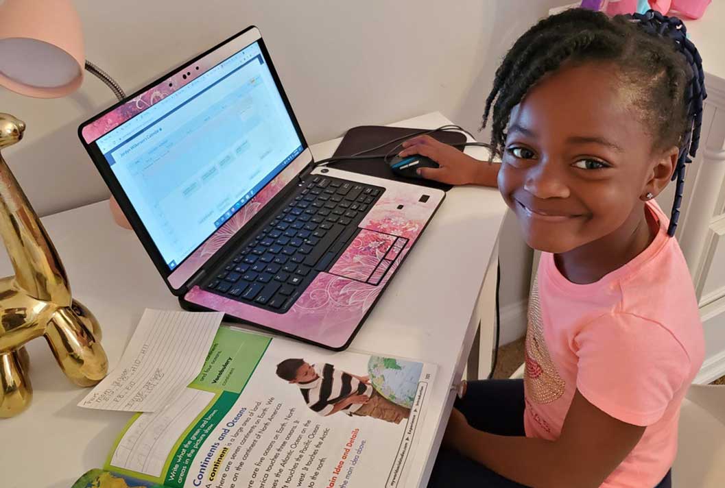 Young student in a pink shirt smiling during their online studies at Connections Academy
