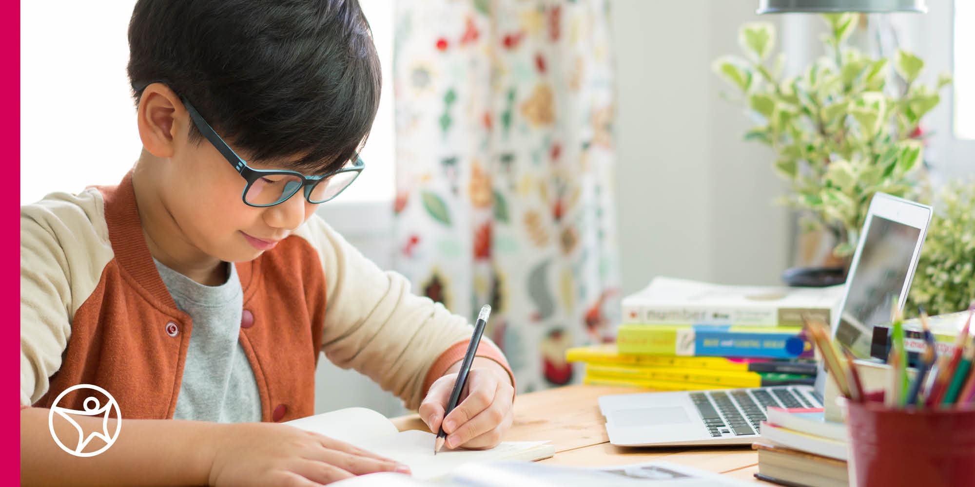 A young boy taking notes in his online class