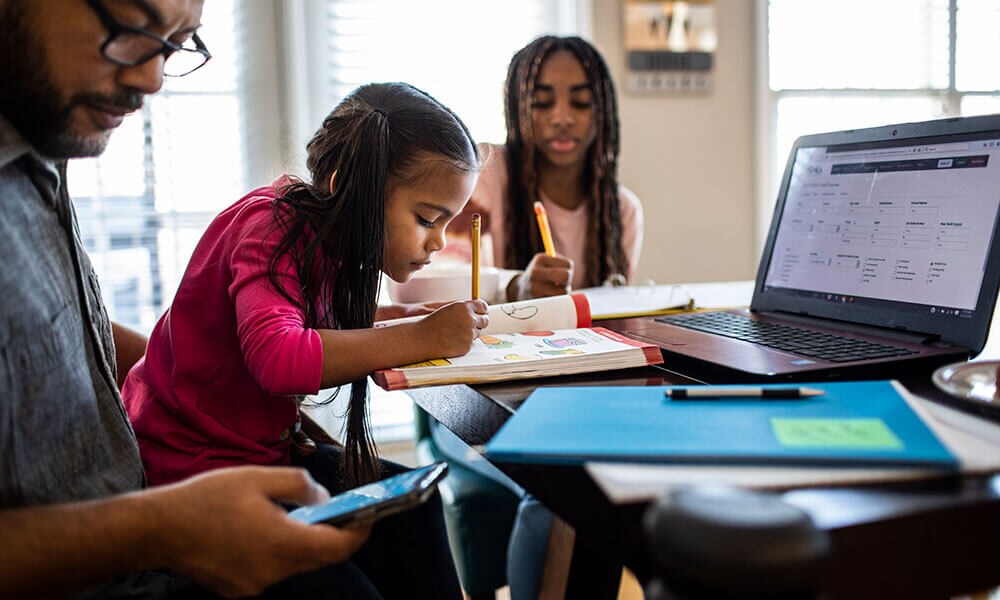 Father helping his daughtesr with their homework
