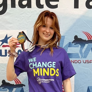 Image of Emma G, a junior at Great River Connections Academy, winning a medal at a Taekwando competition. 