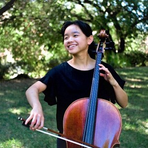 Image of Fiona Tsang, a cellist, National Merit Finalist, and senior at Ohio Connections Academy. She is wearing a black shirt and playing her cello. 
