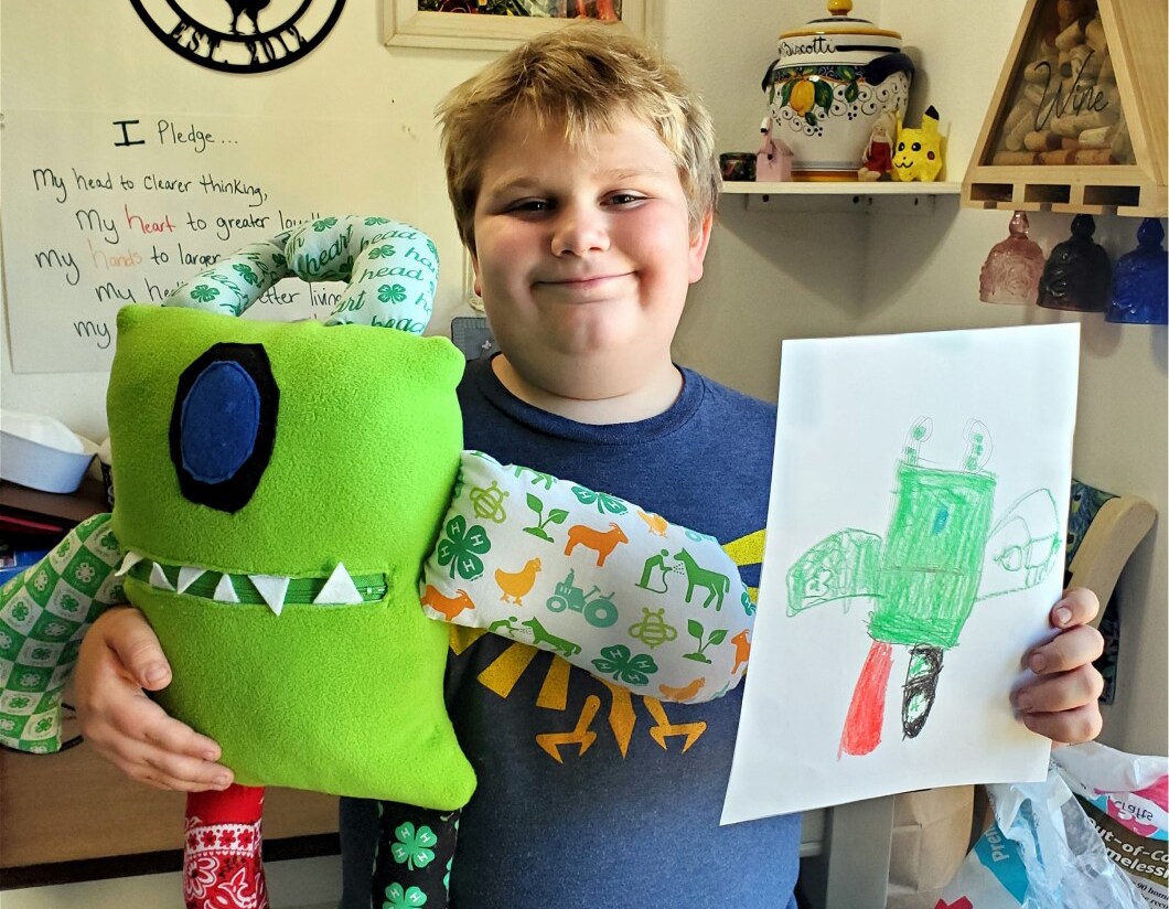 Image of Ben L, a student at Oregon Connections Academy with his worry monster stuffed dolls and original monster drawing.