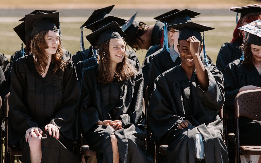 WillCA graduates sitting and smiling at graduation.