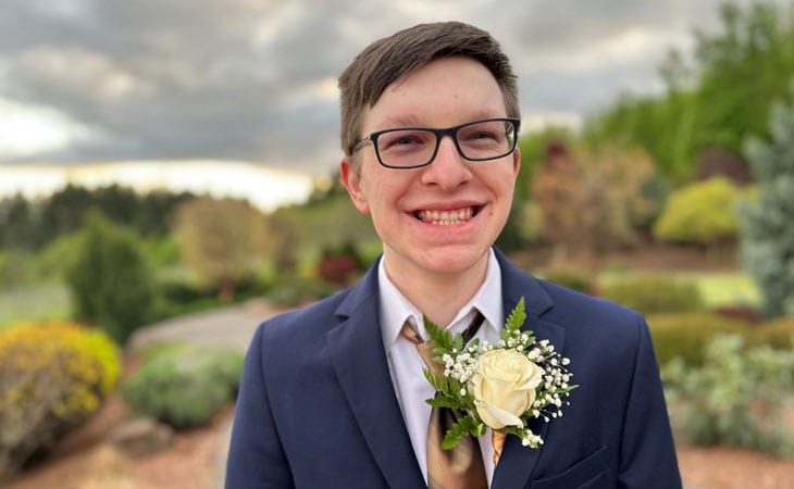 Adam from Willamette Connections Academy pictured here in a blue suit with a flower on his lapel.