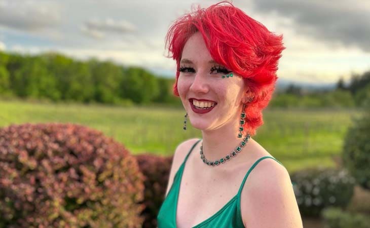 Arowyn is a student from Willamette Connections Academy - she is pictured here in a green dress in front of a green field. 