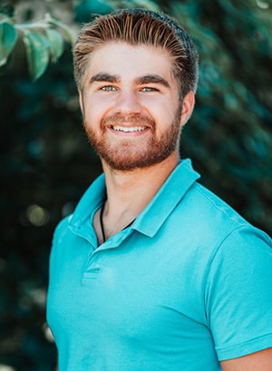 Image of Wyatt Sharkey wewaring a blue polo shirt smiling at the camera. 