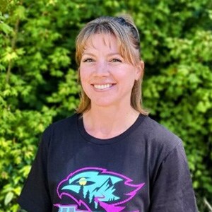 Image of Kelly Shaeffer, Teacher Spotlight for Willamette Connections Academy. She is wearing a black shirt and is standing in front of a green bush.