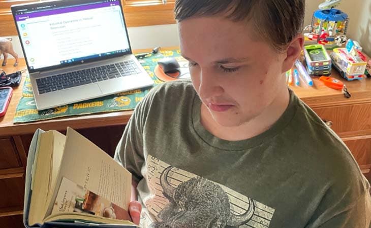Jacob from Wisconsin Connections Academy reading a book while sitting in a green chair