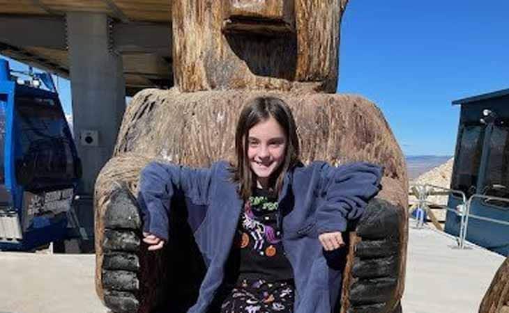 Charlotte from Wyoming Connections Academy in front of a large, carved bear made of wood.