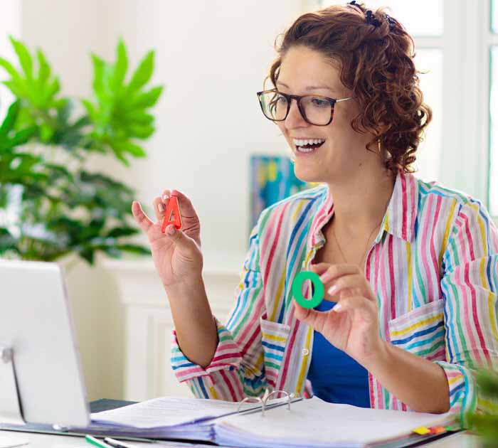 Teacher is holding up letters while teaching an online class