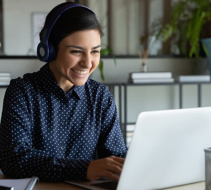 Woman with headset smiling on an online meeting on her laptop