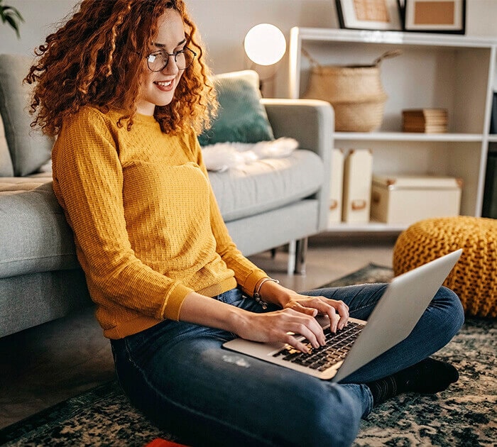 Student sitting on the floor studying on a computer - Connections Academy