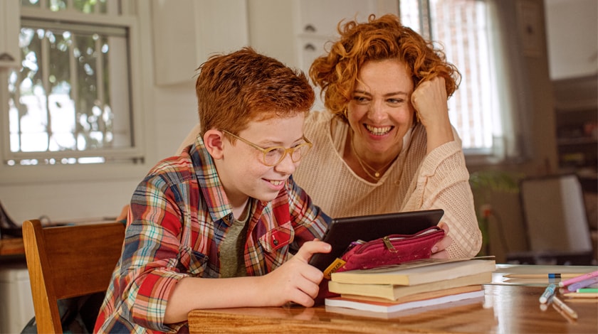 A mother and son are watching an online lesson together  - Connections Academy