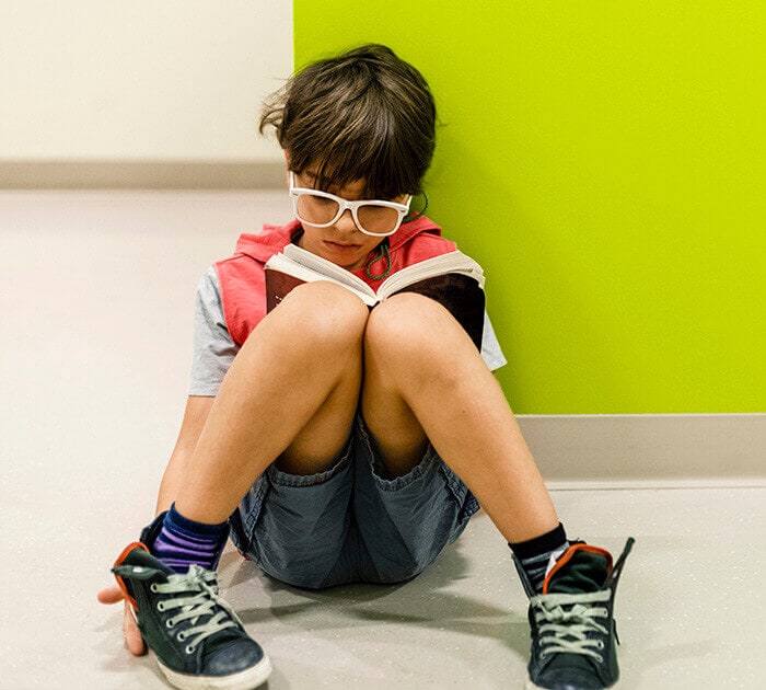 Young student sitting reading a book - Connections Academy