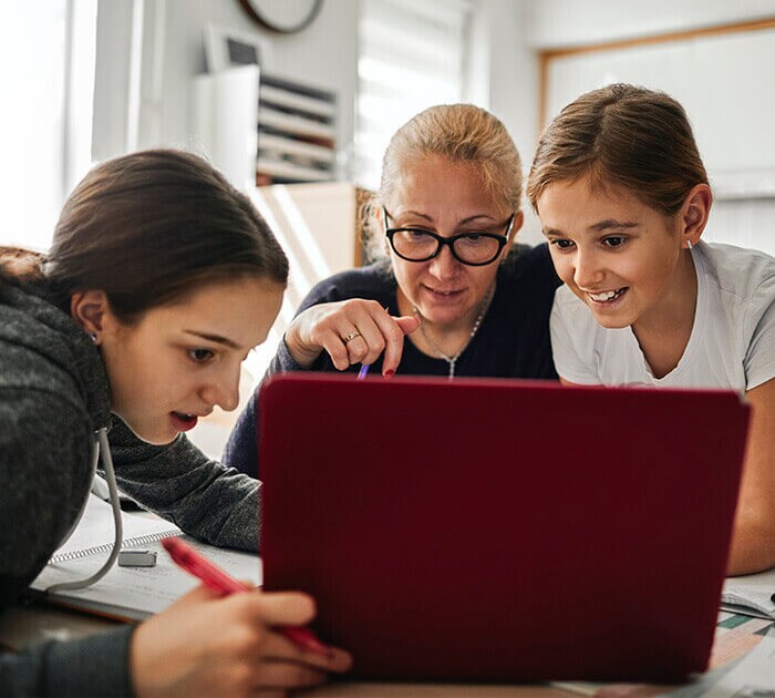 Parent helping two online middle school students on their computer - Connections Academy