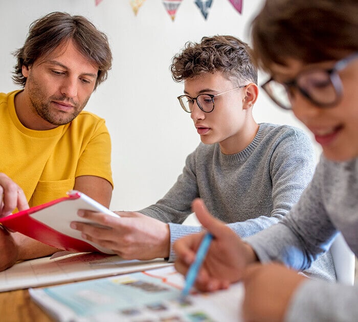 Father and sons studying together at a table - Connections Academy