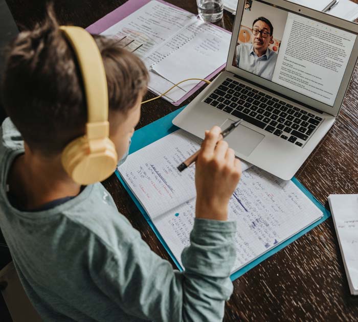 Elementary student sitting in a chair with his laptop - Connections Academy