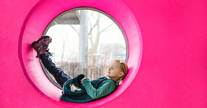 Girl laying down in a circular tub and looking out and above.