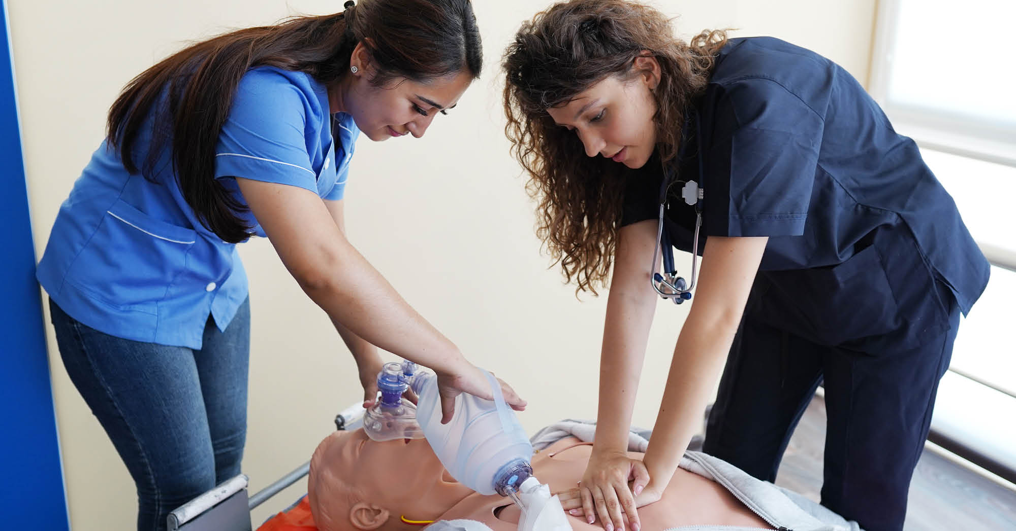 Two high school students performing CPR training on a mannequin - Connections Academy