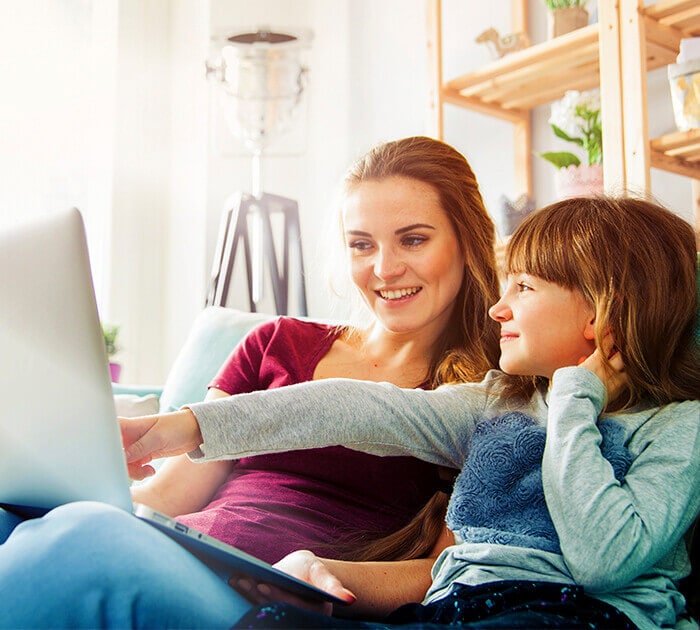 A mother and daughter are looking at a laptop together