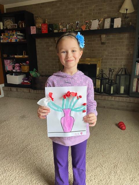 Ava smiling and holding up her flower artwork