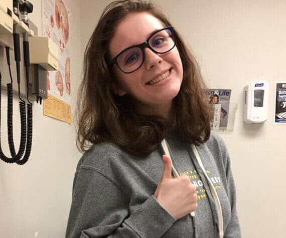 Hannah at a doctor's office with her thumbs up