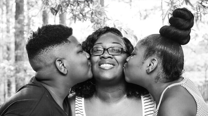 Image of Kalimah and her brother kissing their mother