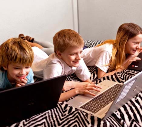 Three students study on a bed with laptops - Connections Academy