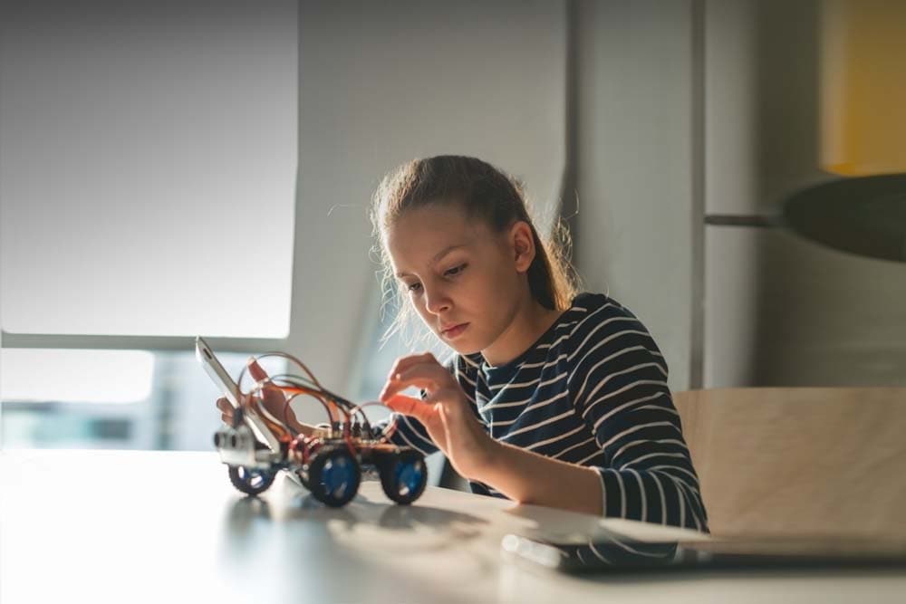 Young female student building a robotic car during an online technology class at Great Lakes Learning Academy