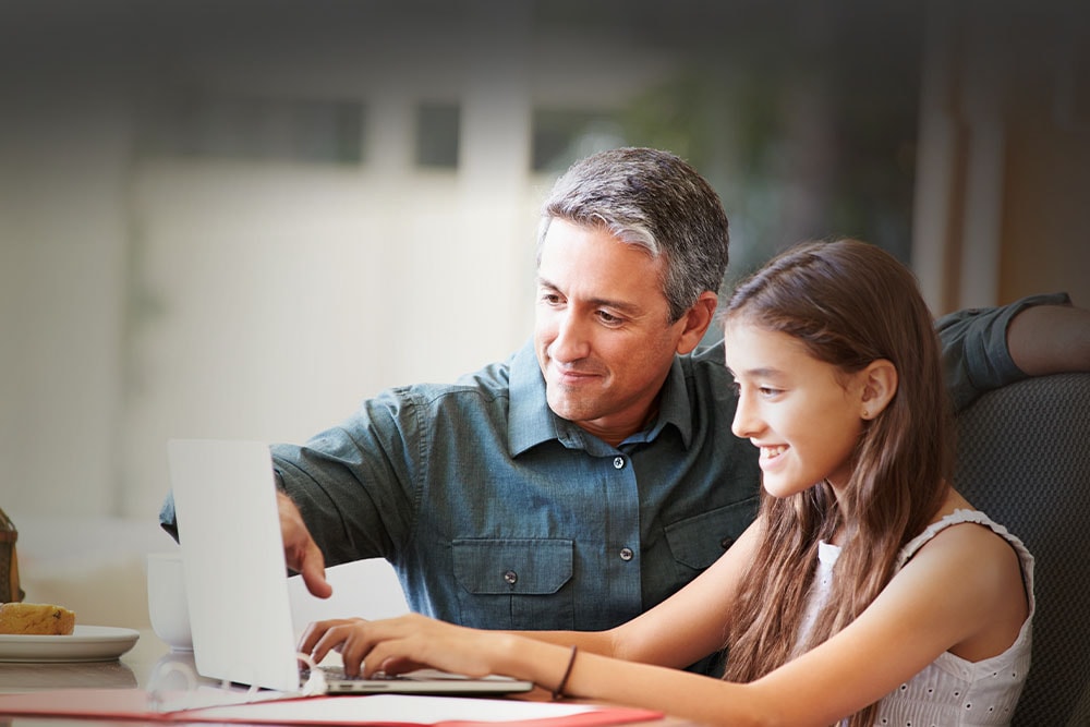 Young girl with learning partner taking an online class smiling at the camera wearing at New Mexico Connections Academy. 