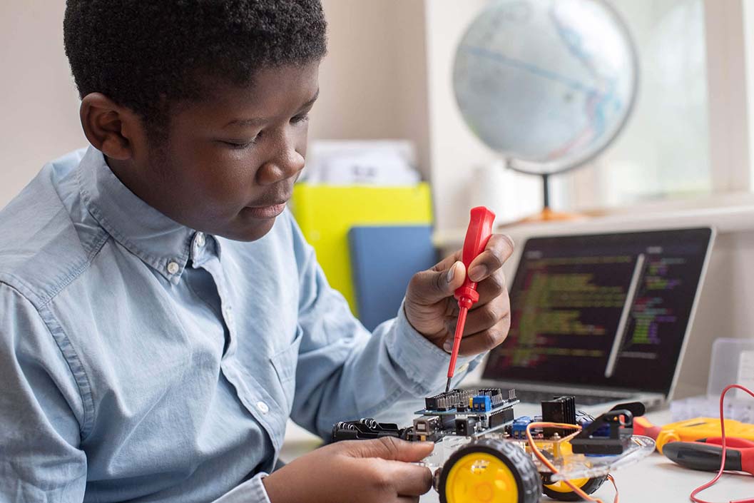 Young boy holding tools working on the electronic toy enjoying his STEM class at Connections Academy