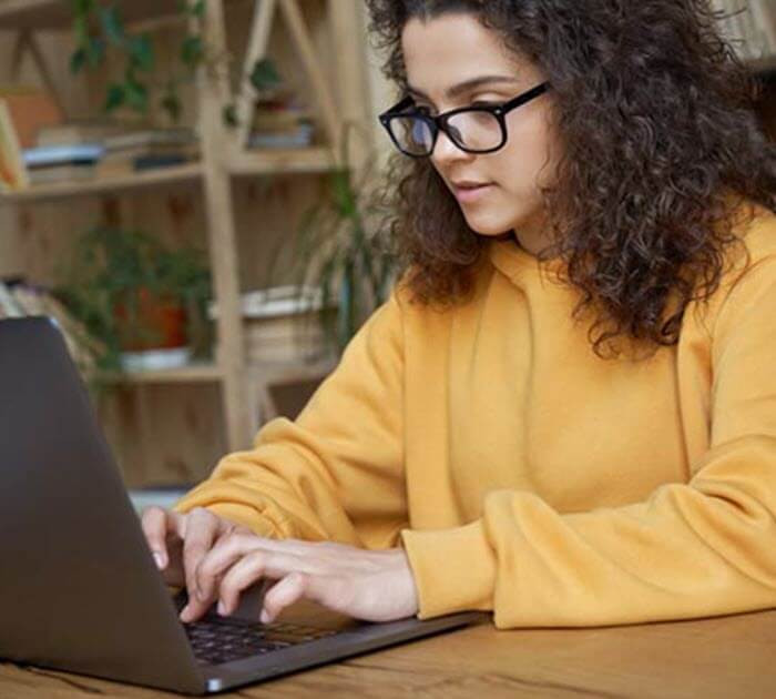 A teenage student taking notes in her online class