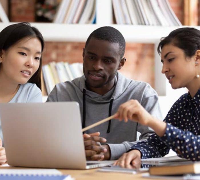 Teenagers sitting arounda laptop studying together - Connections Academy