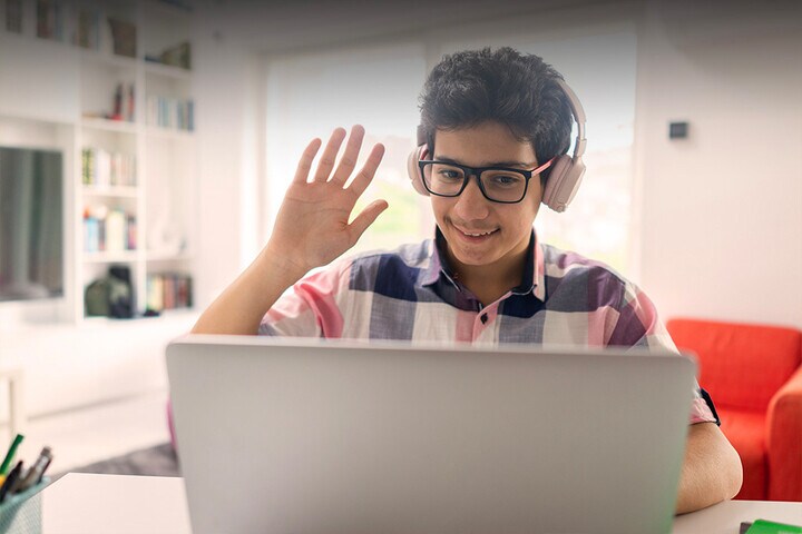 Student at Connections Academy waving to someone on the computer screen.