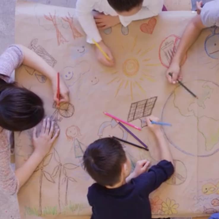 A group of students drawing on a large canvas together