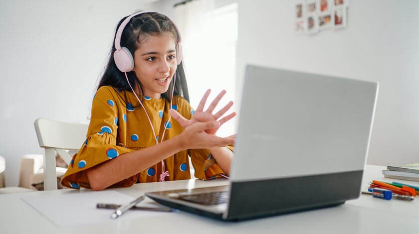 A middle school student is participating in an online class on her laptop