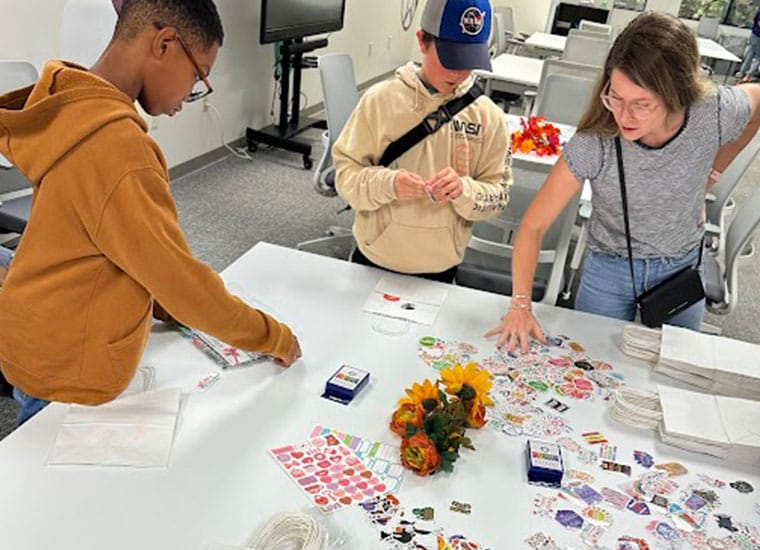Students gathered around a table working on a craft project