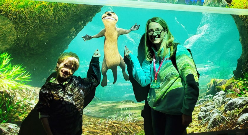 A student and teacher pointing at an otter.