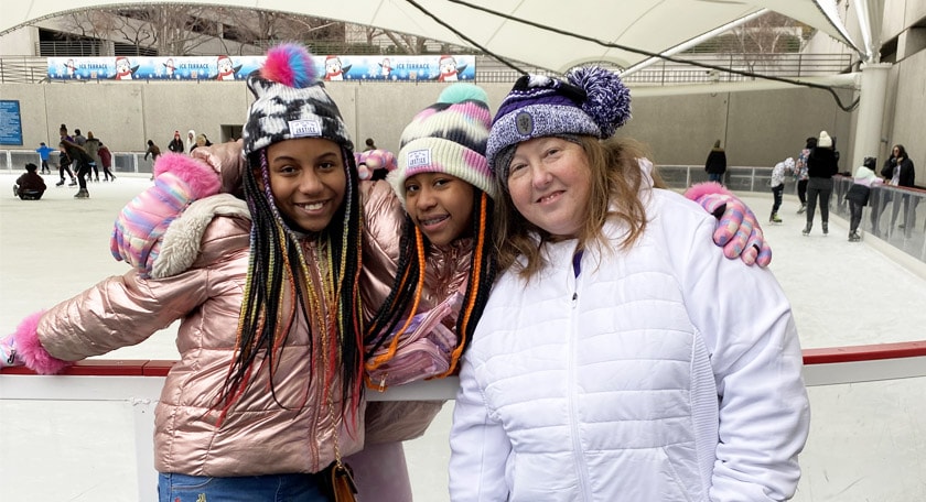 Two students and a teacher posing for a picture by the ice rink.