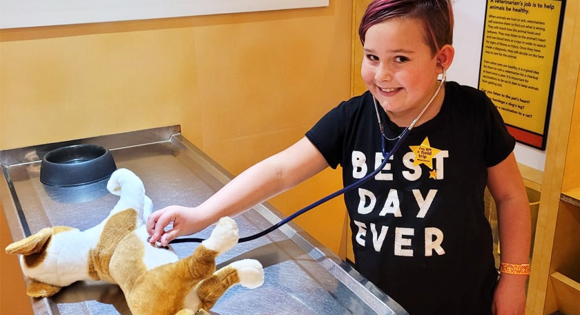 A student pretending to listen to the heartbeat of a stuffed animal.