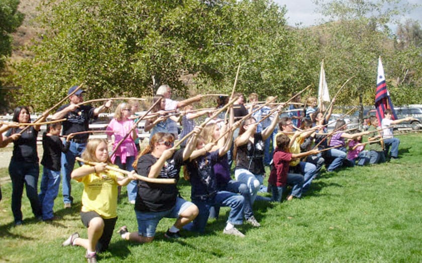 A large group of students are standing in a line holding large sticks in the air