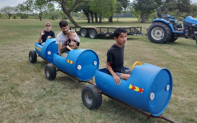A group of elementary students riding in a barrel train at a fall festival