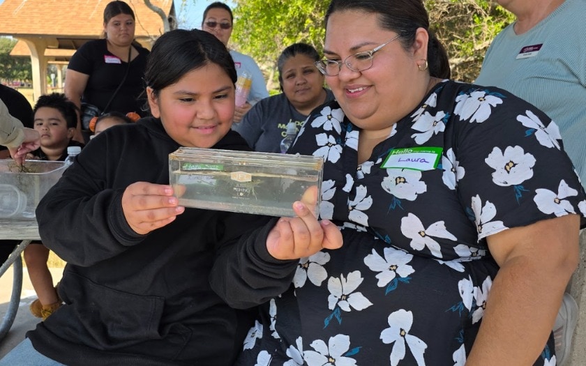 A student and teacher look at an animal in a small box