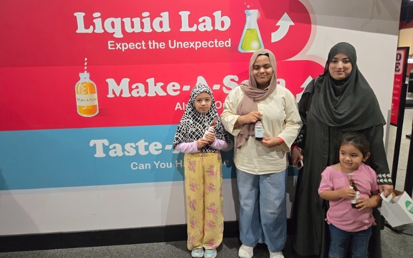 A group of students and parents stand in front of a liquid lab sign