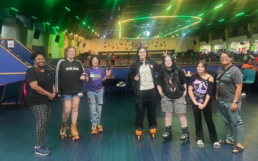 Students are standing in a roller rink with their roller skates on