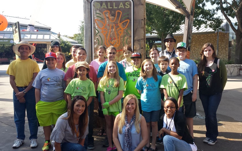 A group of students and teachers standing in front of a Dallas Zoo sign