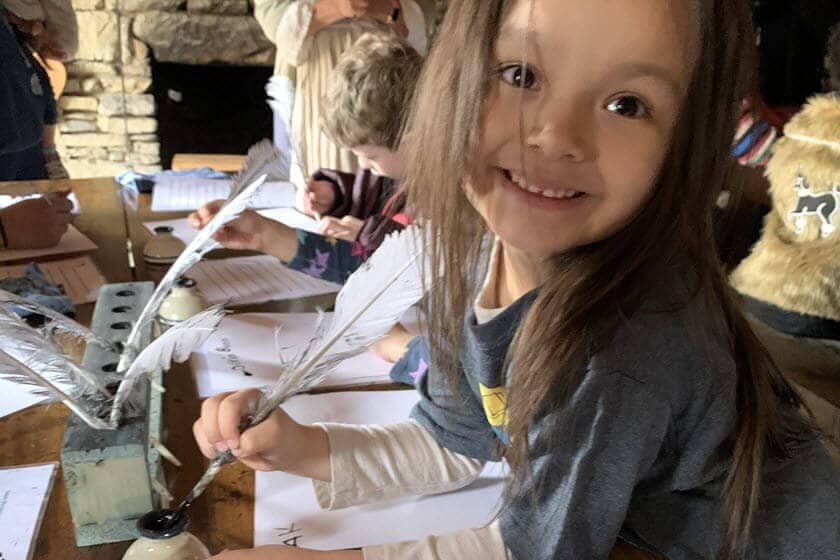 A student is preparing to write with a feather quill and ink