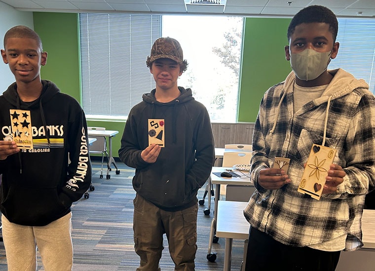 3 students standing in the innovation lab